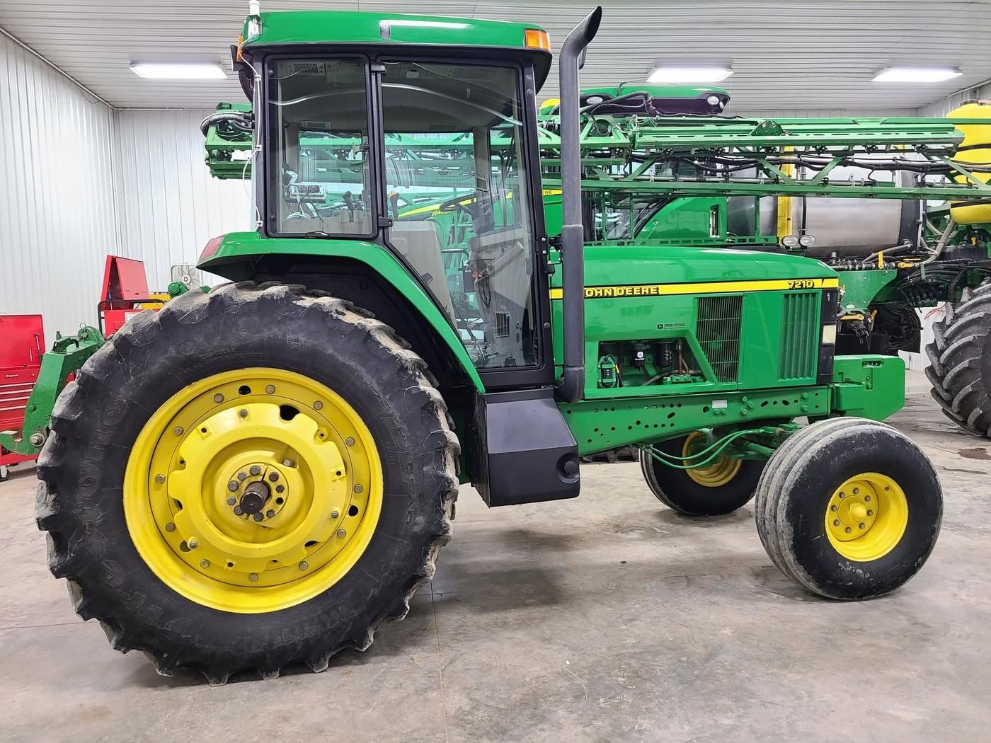 Green John Deere 7210 tractor, side view, cleaned up inside a shop