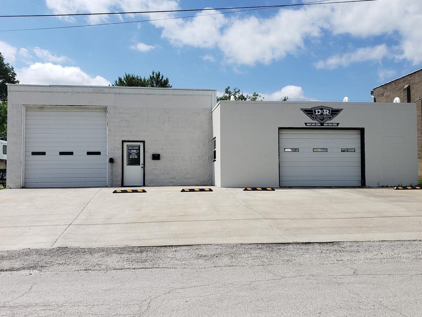 D&R Auto Reconditioning storefront, a white block building with the winged shield sign over the garage door